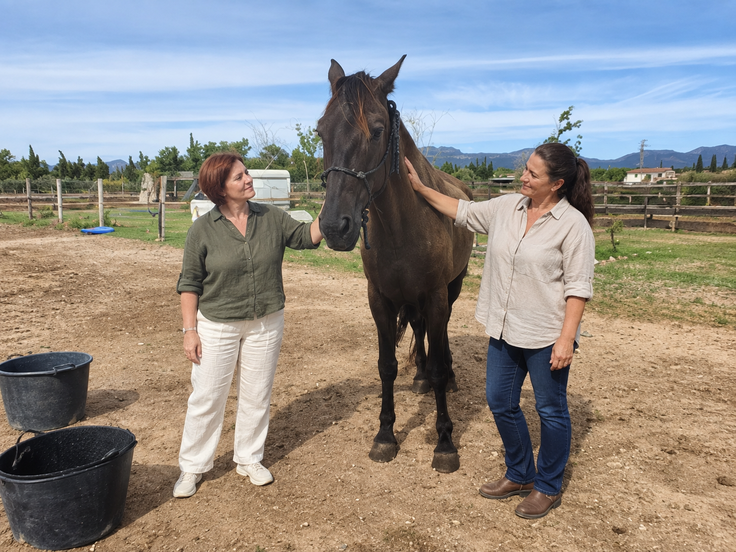 Dos personas junto a un caballo, con la mano apoyada en su cuello en un momento de calma